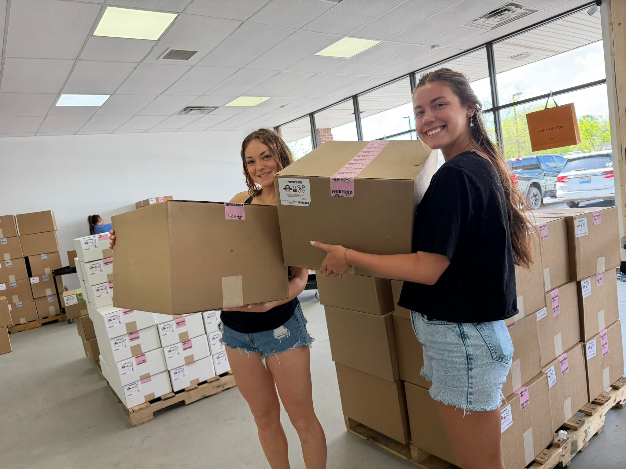 Two shoppers smiling and carrying big mystery boxes in the store