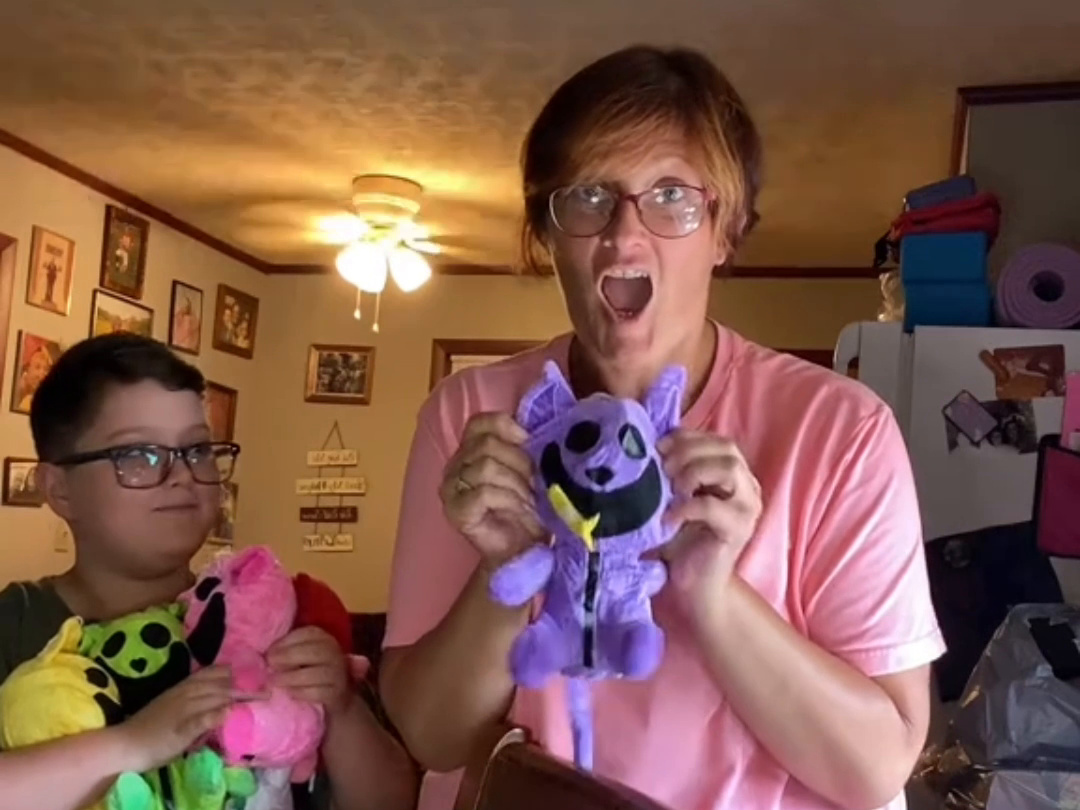 Excited mom at home holding up a plush prize from her mystery box