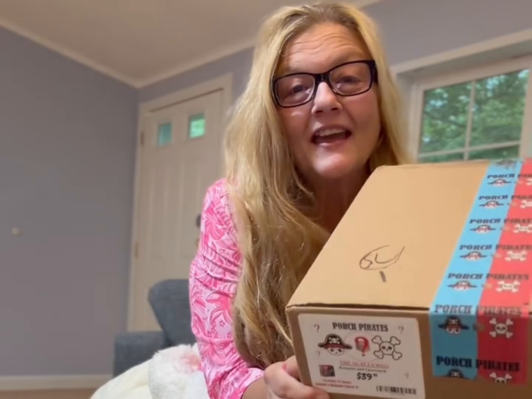 Customer at home on her couch holding her Skallywag mystery box