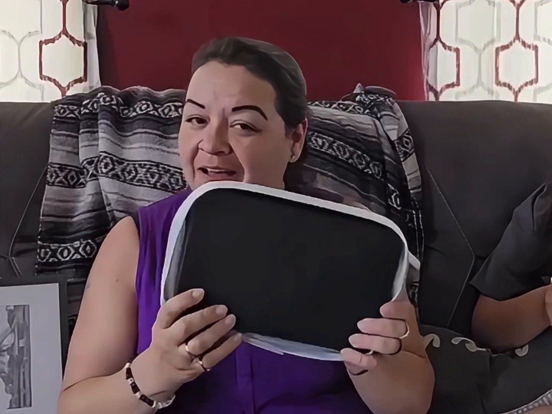 Customer at home on her couch holding up the bag she won