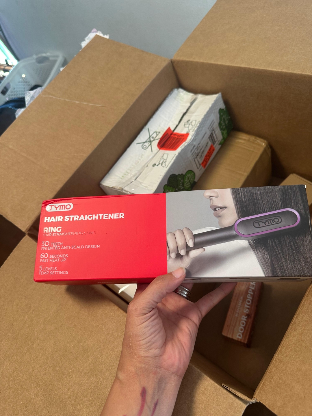 Customer holding a TYMO hair straightener over the open mystery box
